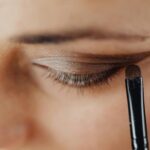 Detailed close-up of an eye being carefully enhanced with eyeshadow using a makeup brush.