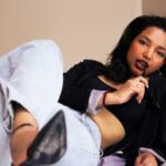 A woman in casual clothes posing stylishly indoors.